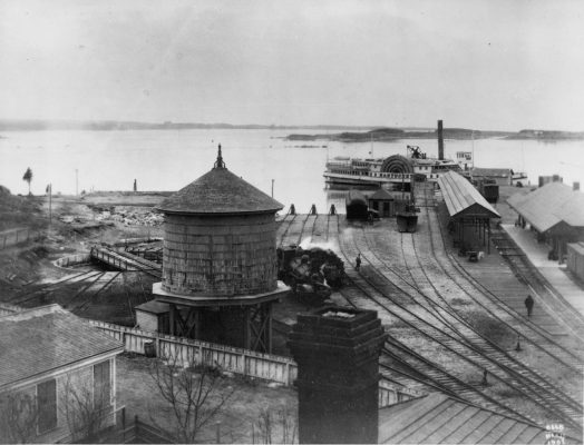 The railroad yard in 1902. The new train terminal is to the right, water tower for steam engine water supply is left. Photo by Baldwin Coolidge.